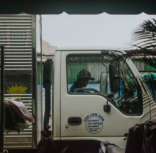 Side profile view of a truck driver inside cab during rain. Urban delivery concept.